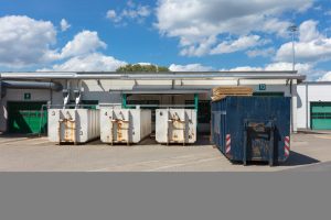 Müllcontainer bei Industrieanlage unter blauem Himmel