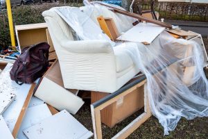 Sperrmüllhaufen mit Möbeln und Rucksack auf Straße.