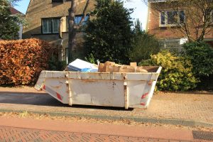 Befüllter Bauschuttcontainer vor Gebäude